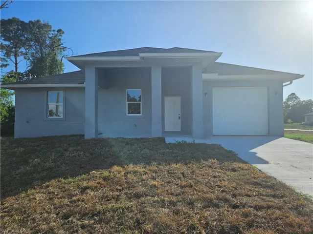 View of front facade with stucco siding, driveway, a front lawn, a garage, and a shingled roof