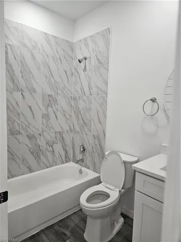 Bathroom featuring tub / shower combination, toilet, vanity, and wood finished floors