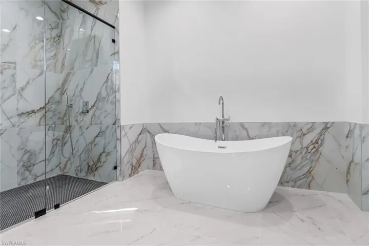 Bathroom featuring tile patterned floors, walk in shower, and tile walls