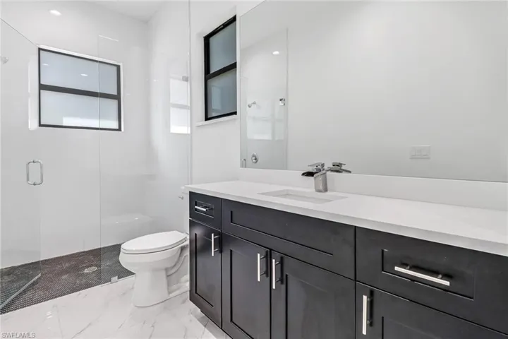 Bathroom featuring tile patterned floors, toilet, vanity, and an enclosed shower