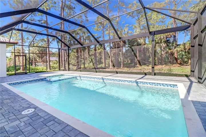 View of pool with a patio area and glass enclosure