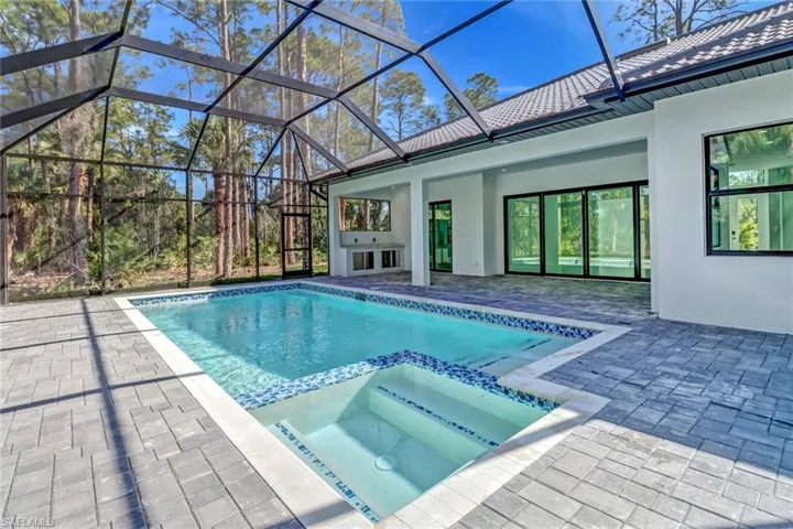 View of swimming pool with a patio area, an in ground hot tub, and a lanai