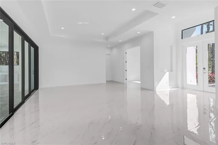 Unfurnished room featuring light tile patterned flooring, french doors, and a raised ceiling