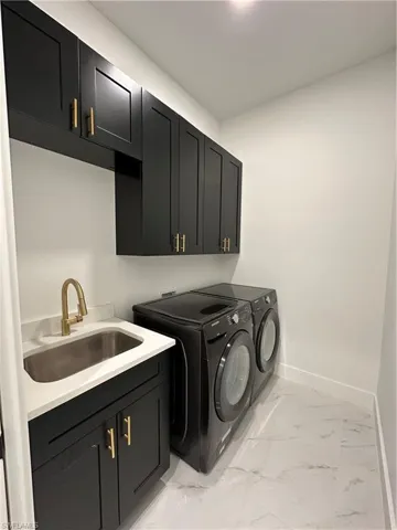 Washroom with cabinets, washer and dryer, and sink
