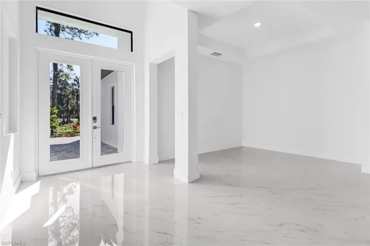 Doorway featuring light tile patterned floors, french doors, and a towering ceiling