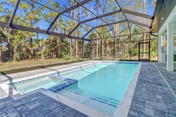 View of pool featuring an in ground hot tub, a patio, and glass enclosure