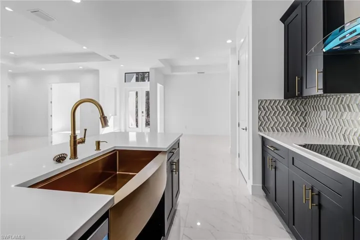 Kitchen featuring range hood, a raised ceiling, tasteful backsplash, and light tile patterned floors