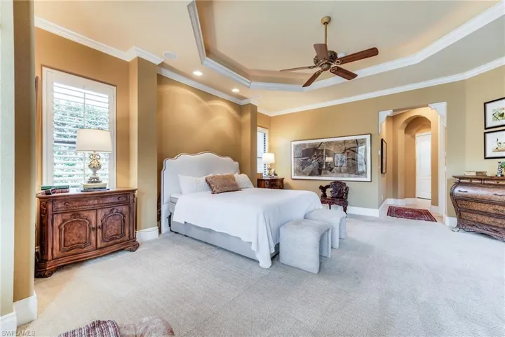 Bedroom with arched walkways, carpet flooring, and crown molding