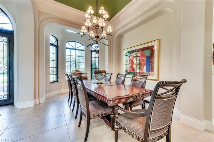 Dining space featuring a chandelier, ornamental molding, baseboards, and light tile patterned floors