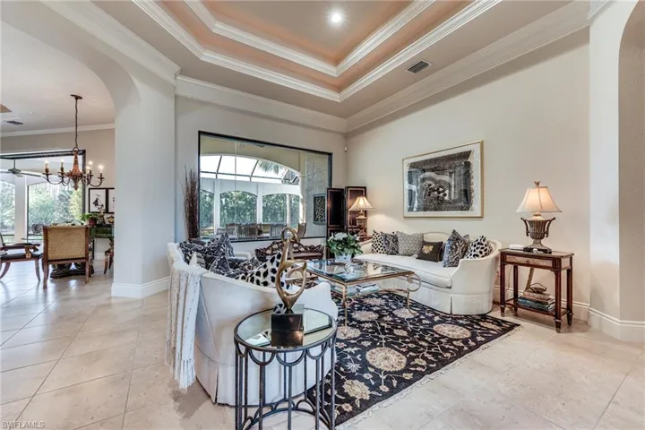 Living room with baseboards, visible vents, ornamental molding, an inviting chandelier, and light tile patterned flooring