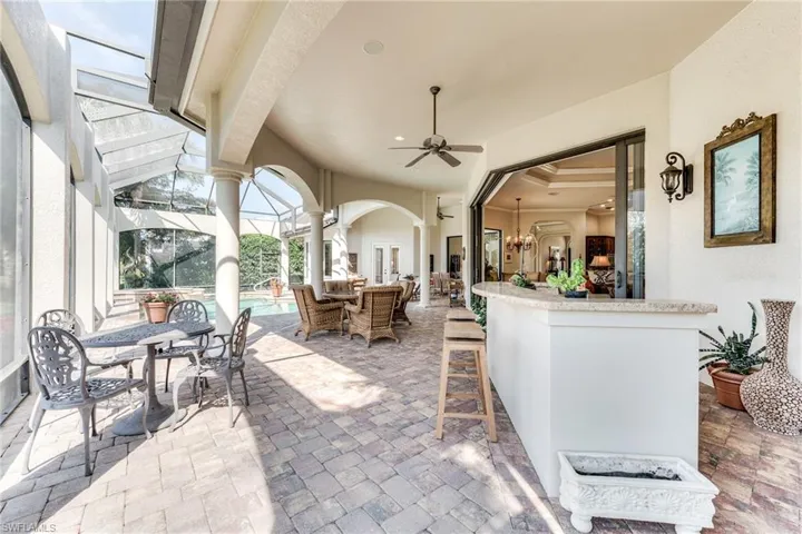 View of patio featuring outdoor dry bar, outdoor dining space, ceiling fan, a lanai, and an outdoor pool