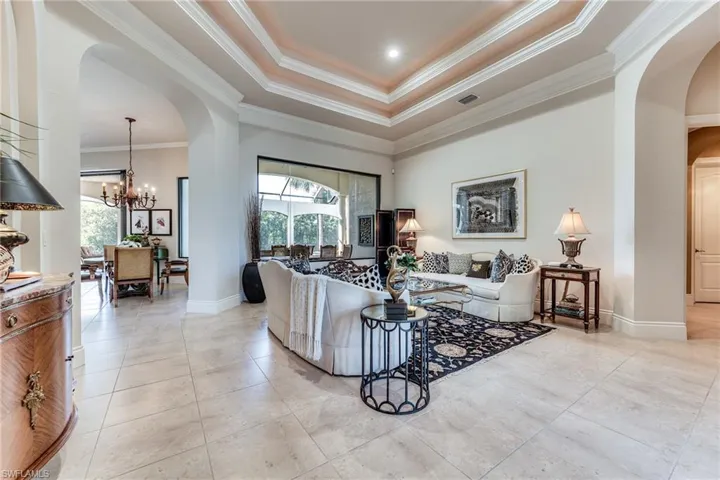 Living room featuring arched walkways, visible vents, a chandelier, and a wealth of natural light