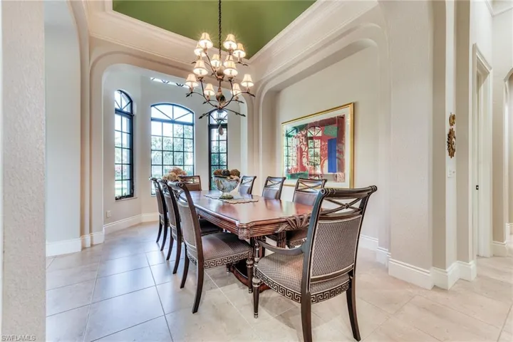 Dining area featuring baseboards, an inviting chandelier, light tile patterned flooring, and crown molding