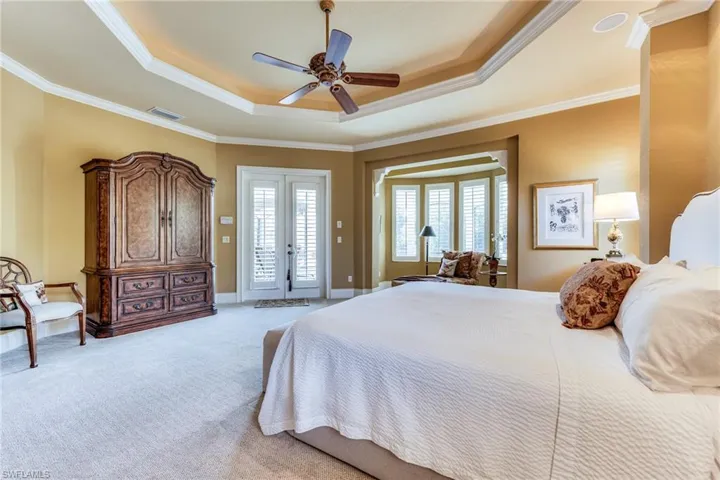 Bedroom featuring access to outside, a tray ceiling, french doors, and light colored carpet