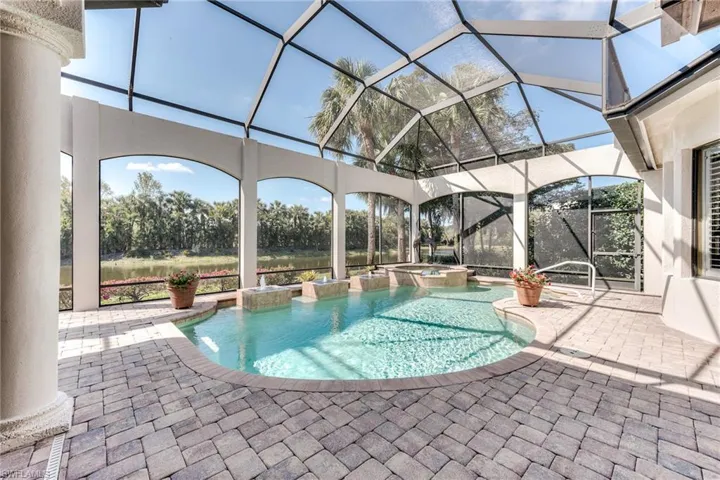 View of pool featuring a patio area, a pool with connected hot tub, and glass enclosure
