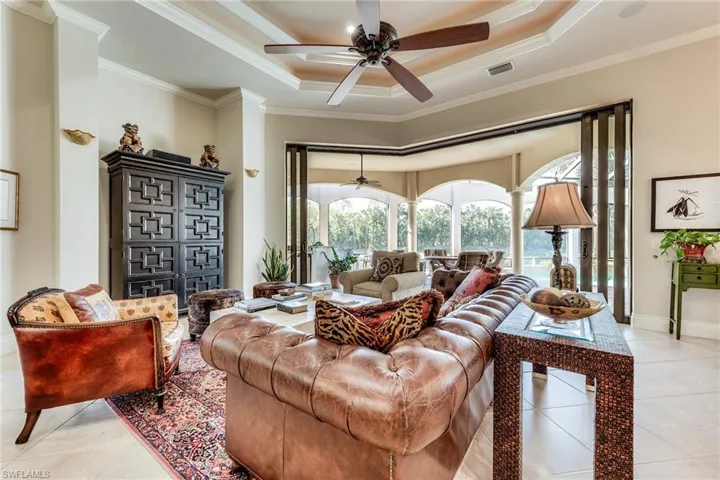 Living room featuring ornamental molding, a tray ceiling, light tile patterned flooring, and visible vents
