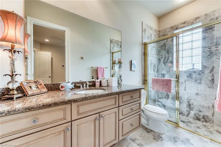 Bathroom featuring toilet, a stall shower, and vanity