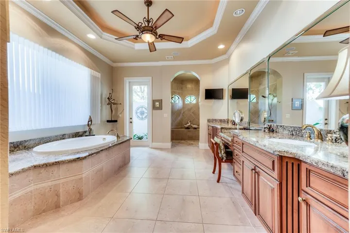Bathroom featuring crown molding, a tray ceiling, vanity, and tile patterned floors