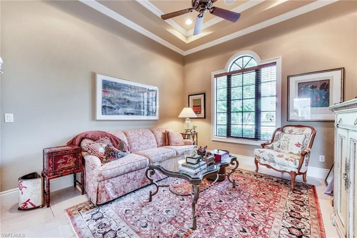 Tiled living room featuring baseboards, plenty of natural light, a raised ceiling, and crown molding