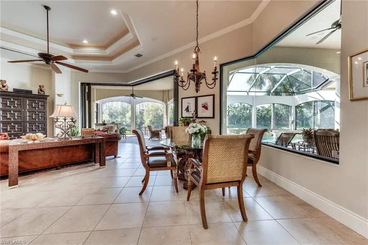 Dining area with a tray ceiling, crown molding, a ceiling fan, a sunroom, and baseboards