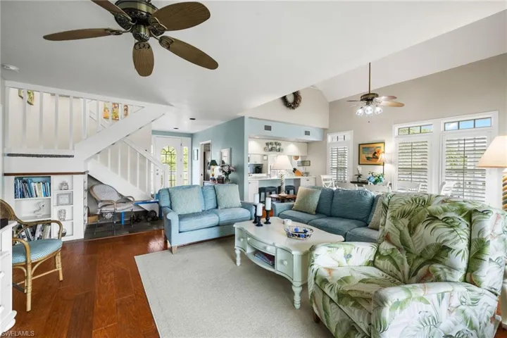 Living room with a healthy amount of sunlight, vaulted ceiling, ceiling fan, and dark hardwood / wood-style flooring
