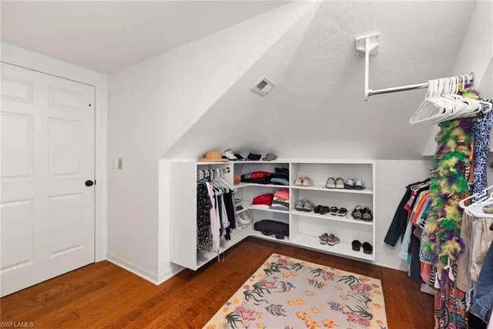 Walk in closet with vaulted ceiling and dark hardwood / wood-style floors