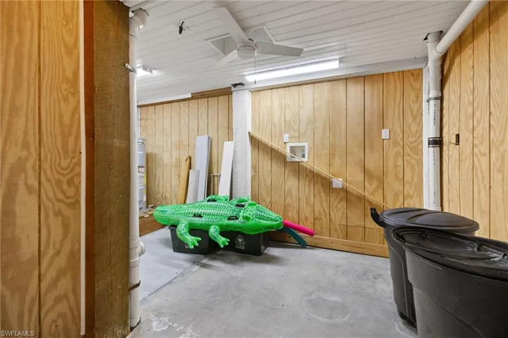 Rec room with ceiling fan, concrete floors, and wood walls