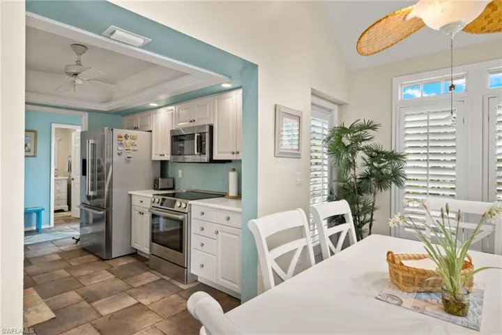 Kitchen featuring ceiling fan, tasteful backsplash, white cabinetry, stainless steel appliances, and lofted ceiling