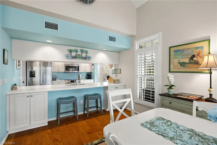Kitchen featuring appliances with stainless steel finishes, white cabinets, sink, kitchen peninsula, and a breakfast bar