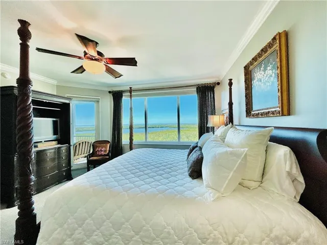 Expansive windows with water views, crown molding, ceiling fan, and built-in media cabinetry