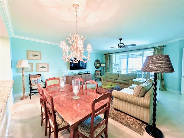 Open-concept living area with crown molding, a built-in media console, ceiling fan, and sliding glass doors to outdoor space