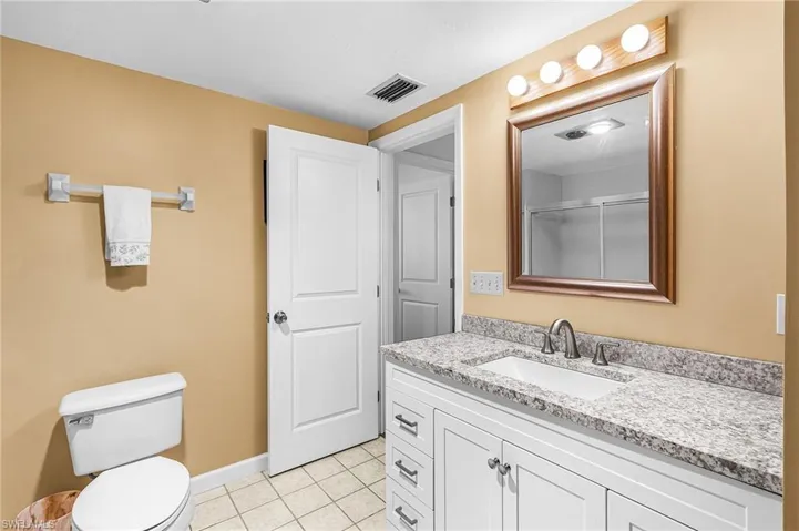 Full bath with a stall shower, vanity, and light tile flooring