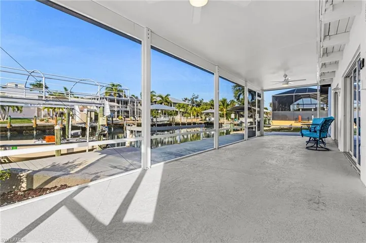View of screened porch featuring ceiling fan, a water view, boat lift and a boat dock