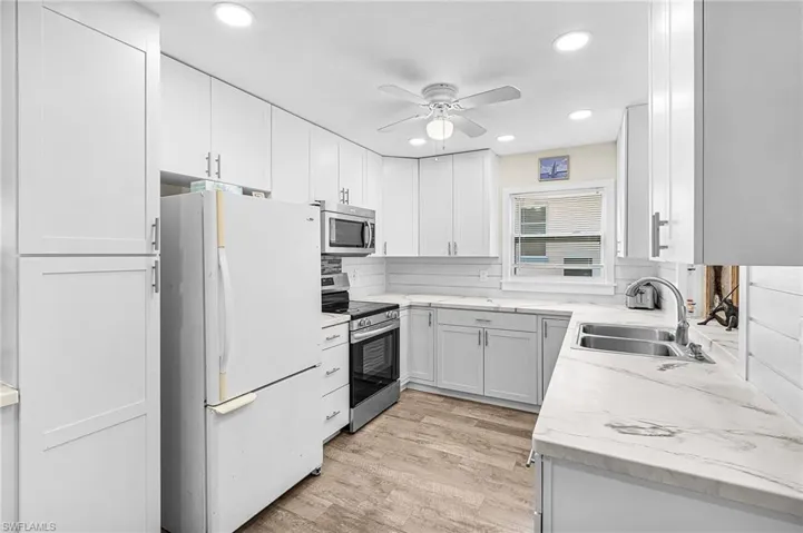 Kitchen featuring appliances with stainless steel finishes, recessed lighting, light wood-style flooring, ceiling fan, and light counters