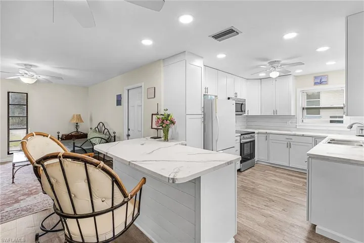 Kitchen with a ceiling fan, a kitchen breakfast bar, light counters, some stainless steel appliances, and recessed lighting
