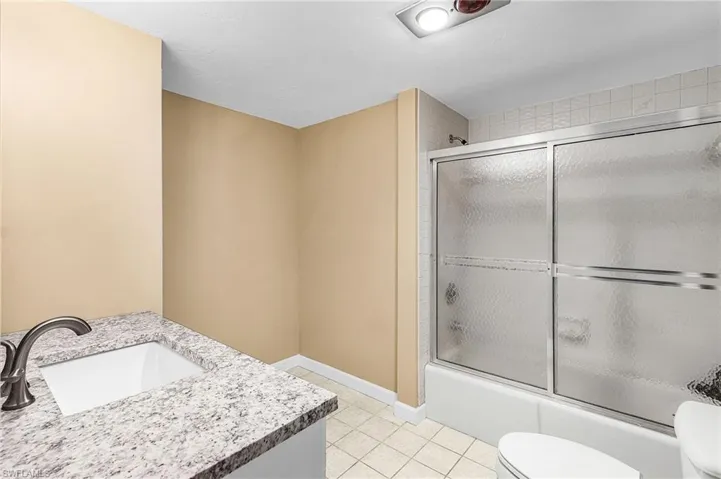 Bathroom with vanity, enclosed tub / shower combo, and light tile floors