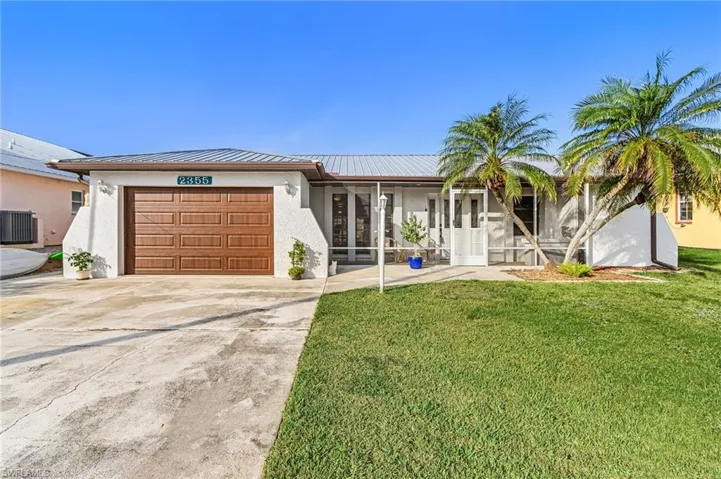 Ranch-style home featuring stucco siding, a front yard, an attached garage, and driveway
