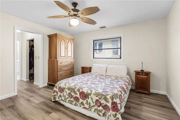 Bedroom with light wood-style flooring, a ceiling fan, and a spacious closet