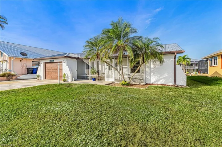 View of front of house featuring a front lawn, a garage, driveway, and stucco siding