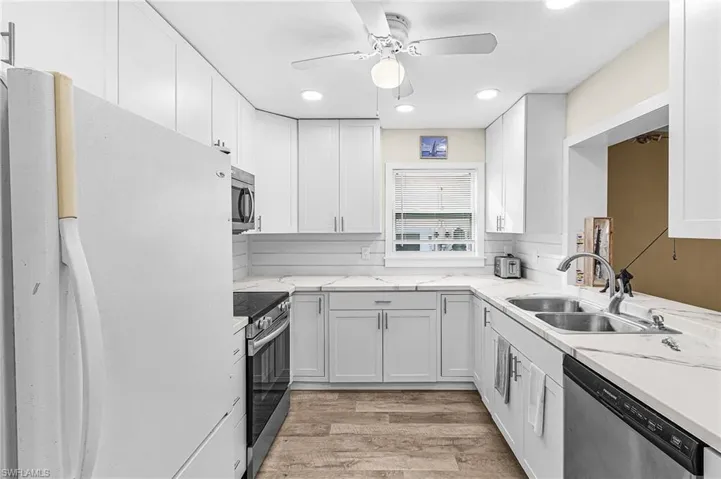 Kitchen with appliances with stainless steel finishes, light wood-type flooring, ceiling fan, recessed lighting, and white cabinetry