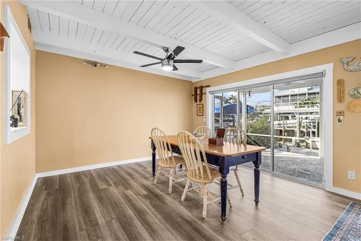 Dining area with a ceiling fan, LVP floors, and a wooden ceiling with exposed beams