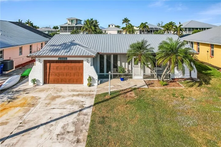 View of front of property with a front yard, driveway, stucco siding, an attached garage, and a metal roof