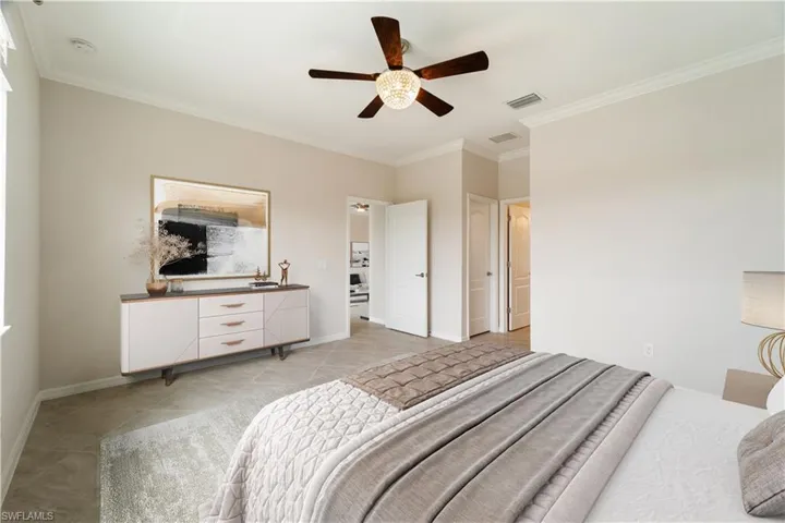 Virtually Staged Primary Bedroom featuring ceiling fan, crown molding, en suite bath and large walk in closet.