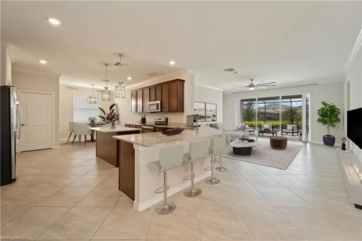 Virtually Staged Kitchen with stainless steel appliances, light stone counters, crown molding, sink, and light tile patterned floors.