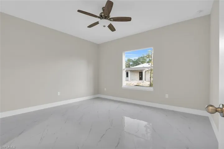 Bright room featuring light gray walls, white baseboards, and large format marble-look tile flooring