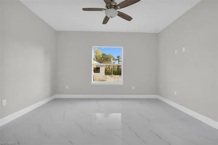 Spacious room featuring light gray walls, white baseboards, and large format tile flooring