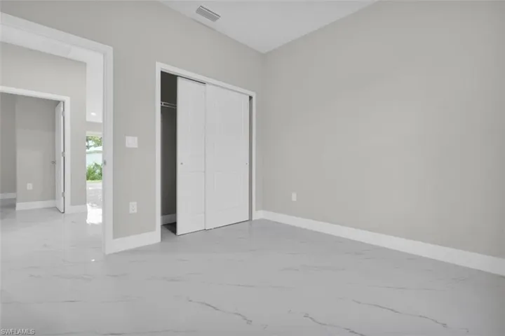 Spacious room featuring light gray walls, white baseboards, and marble-look tile flooring