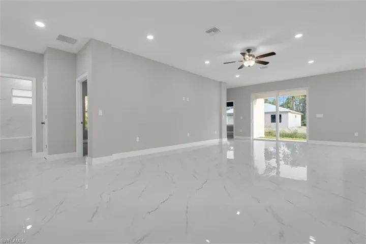 Spacious living area featuring polished white tile flooring, recessed lighting, a ceiling fan with integrated light fixture, light gray wall paint, and white baseboards