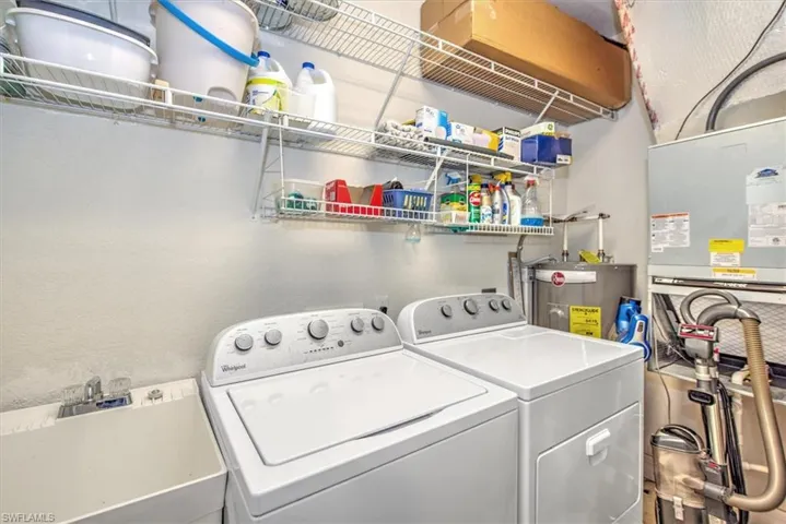 Laundry area featuring sink, electric water heater, and washing machine and clothes dryer