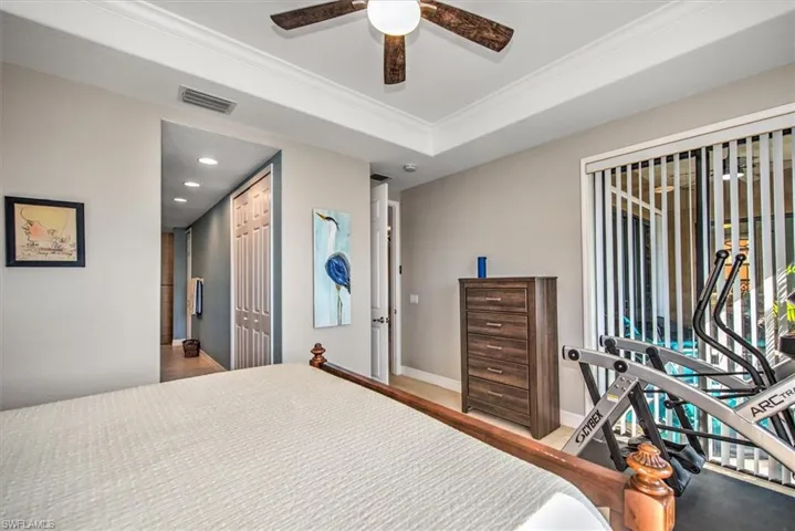 Bedroom with ceiling fan, a raised ceiling, a closet, and crown molding